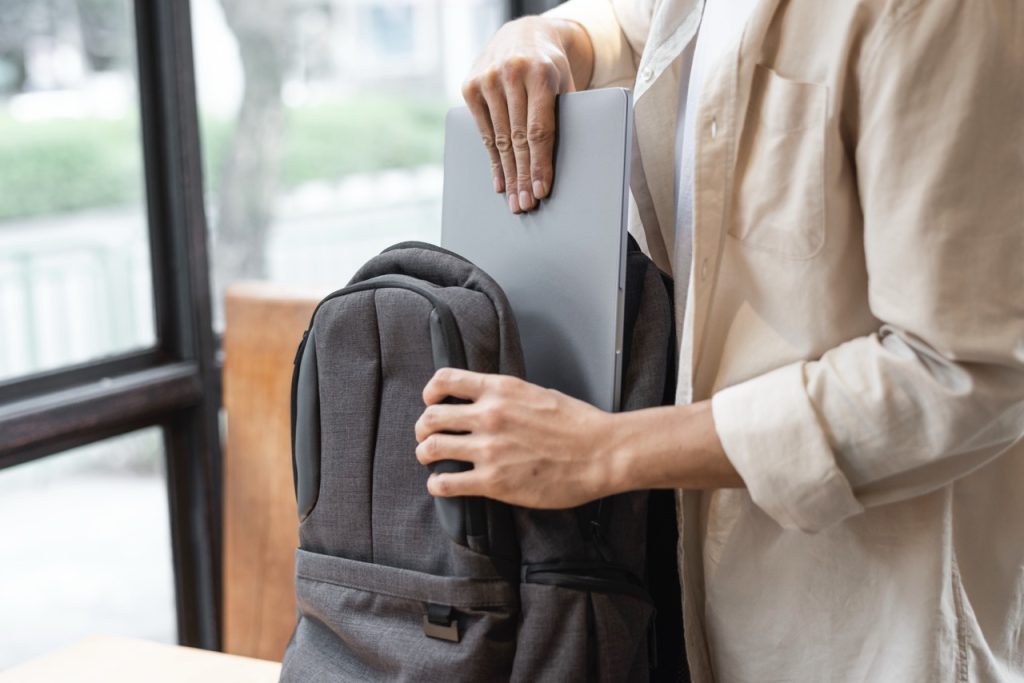 Person placing a custom t-shirt into a backpack at a promotional item store.
