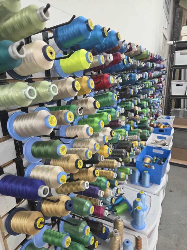 Assorted colorful thread spools on display at QC Custom Tees for custom apparel printing.